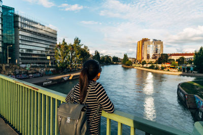 Rear view of woman on bridge over river in city
