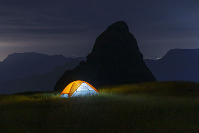 Illuminated tent on mountain against sky at night