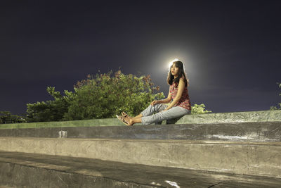 Side view of woman sitting on the wall