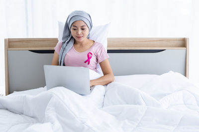Smiling young woman sitting on bed