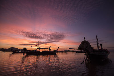 Silhouette boats moored on sea against sky during sunset