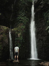 Rear view of man standing by waterfall