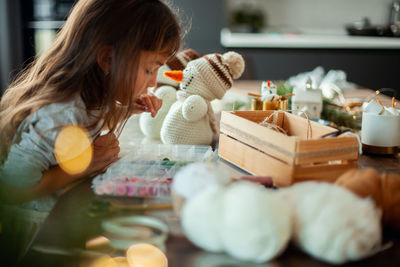 Rear view of girl sitting on table at home