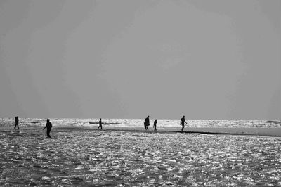 People on beach against clear sky