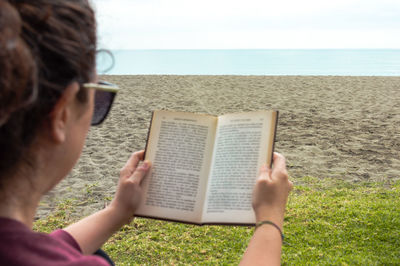 Midsection of woman reading book on beach