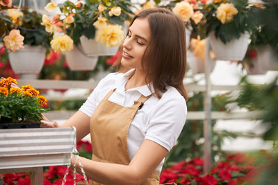 Young woman standing against white flowering plants
