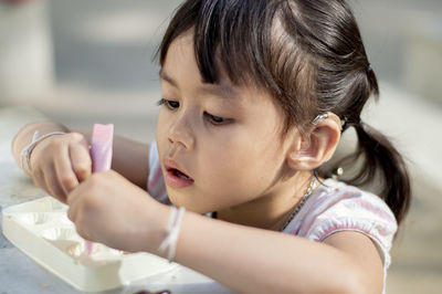 Close-up of cute girl playing with childs play clay at table outdoors