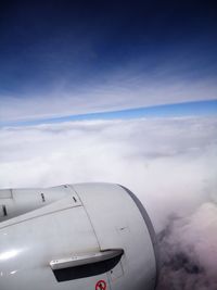 Airplane flying over clouds against blue sky