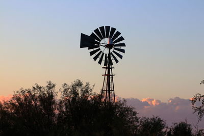 Low angle view of traditional windmill against sky during sunset