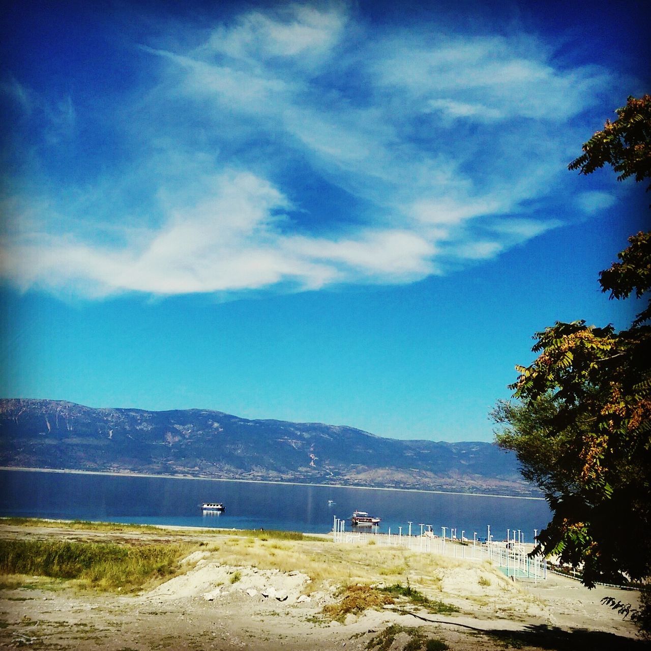 water, mountain, sky, tranquil scene, tranquility, scenics, lake, beauty in nature, mountain range, tree, nautical vessel, nature, cloud - sky, boat, blue, transportation, cloud, idyllic, river, moored