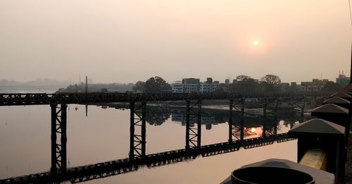 Bridge over river against sky during sunset