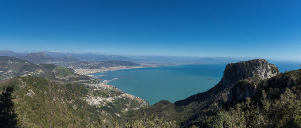 High angle view of sea and mountains against blue sky