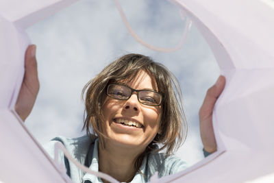 Smiling woman wearing eyeglasses seen through shopping bag