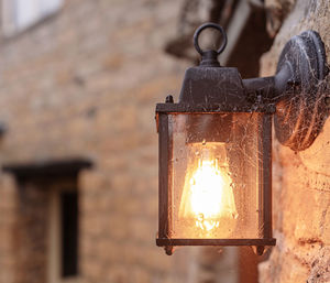 Low angle view of illuminated light bulb against wall