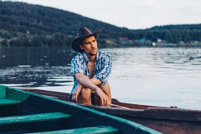 Young man sitting in boat on lake