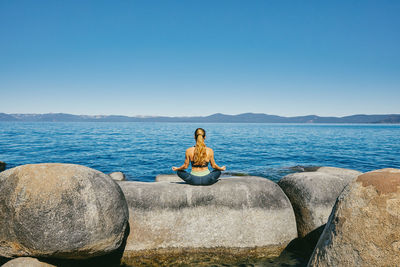 Young woman practicing yoga on lake tahoe in northern california.