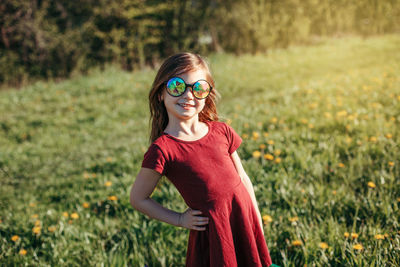 Portrait of smiling girl wearing sunglasses standing on field