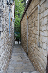 Rear view of people walking on footpath amidst buildings