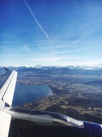 Aerial view of airplane wing over landscape against blue sky