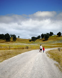 Rear view of people riding on road against sky