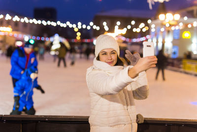 Portrait of young woman standing on street at night