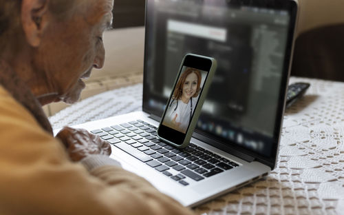 Senior woman consulting doctor on video call through smart phone at home