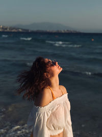 Woman with tousled hair standing at beach