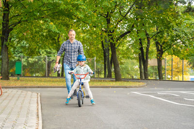 Rear view of man riding bicycle on road