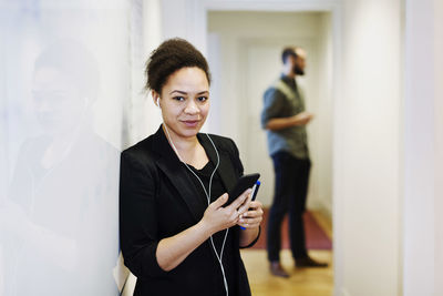 Portrait of businesswoman listening music through headphones using mobile phone in office