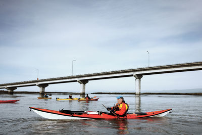 Senior man kayaking on river against sky