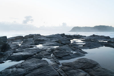 Rocks on sea shore against sky