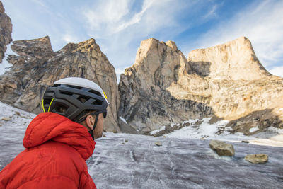 Climber wearing helmet looks up at mount asgard
