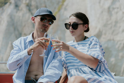 A young guy pours champagne while sitting in a boat at sea.