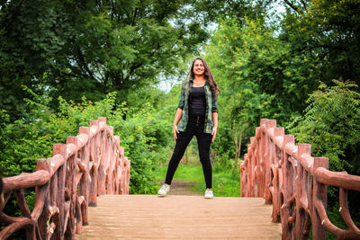 Portrait of smiling woman standing on footbridge