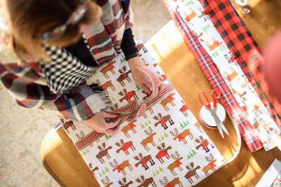 High angle view of woman wrapping gift at home