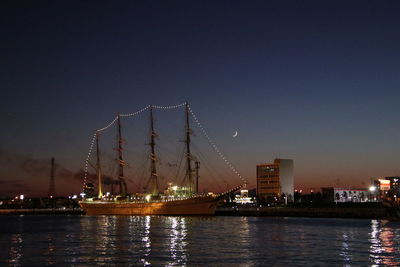 River by illuminated city against clear sky at night