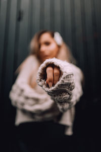 Low angle view of woman wearing sweater against wall