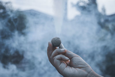 Cropped hands burning firework outdoors