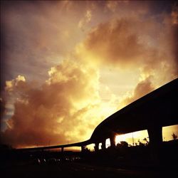 Low angle view of bridge against cloudy sky