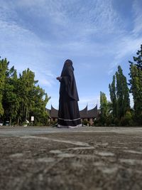 Rear view of woman walking on cross against sky