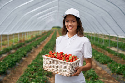 Portrait of a smiling young woman standing in basket