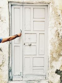 Hand of person knocking door of weathered building