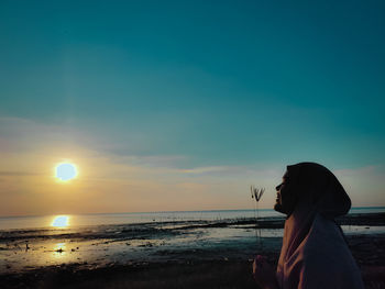 Woman on beach against sky during sunset
