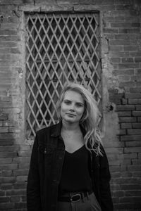 Portrait of woman standing against brick wall