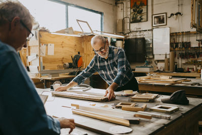 Senior male carpenter examining timber on workbench at repair shop