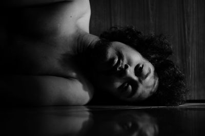 Close-up portrait of shirtless man lying on floor