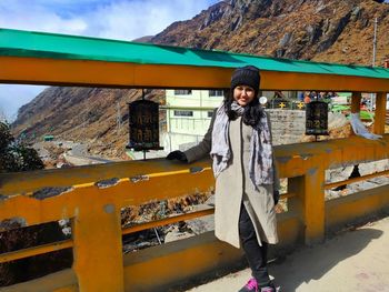 Portrait of young woman standing against mountain