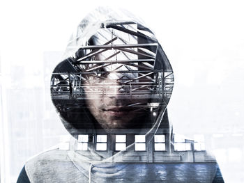 Double exposure of architecture and man wearing hooded jacket