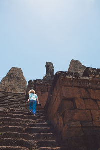 Rear view of woman moving up on steps at temple