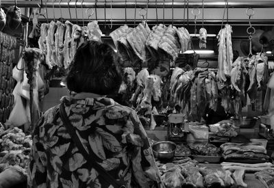 Rear view of woman buying meat at butchers shop